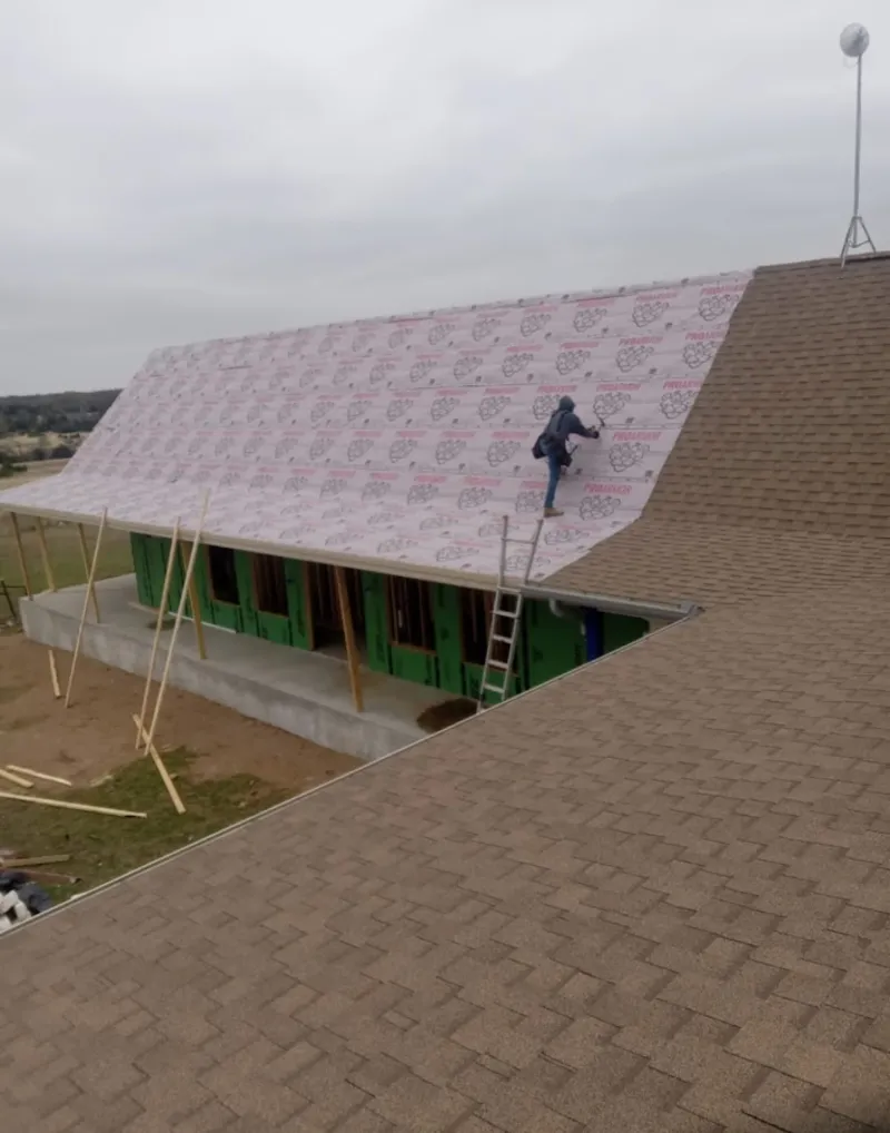 Worker preparing underlayment for a metal roof installation in Aldine